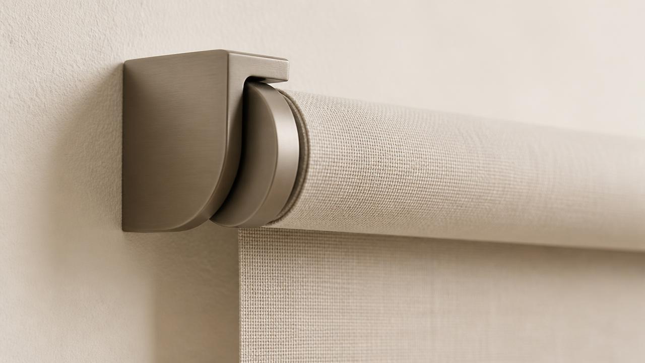 Close view of a matte metal bracket fixed to a plain white wall, holding the top tube of a woven fabric roller shade